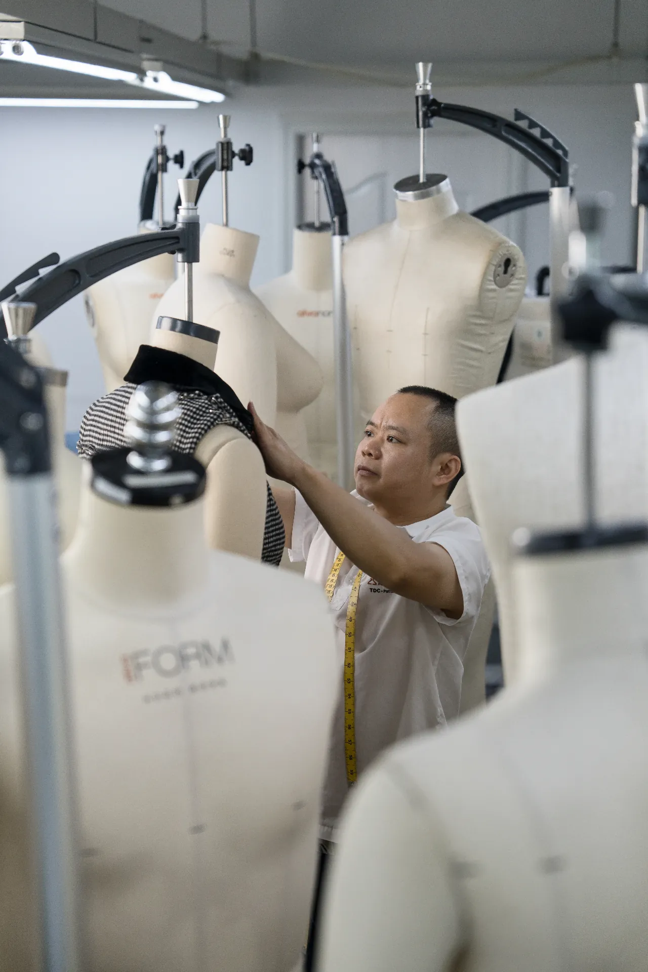 Pattern maker working among dress forms in a production studio.